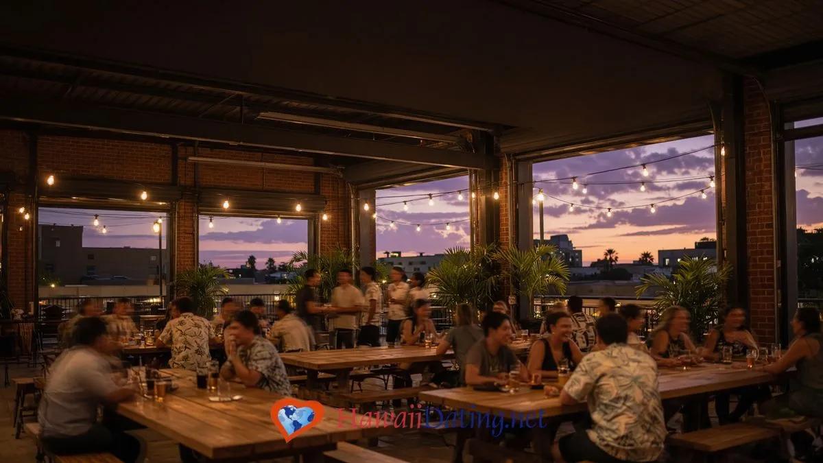 Open-air Honolulu brewery taproom at dusk with string lights and people gathered at communal wooden tables